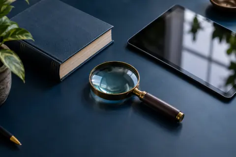 Loupe, livre de référence et tablette sur une table